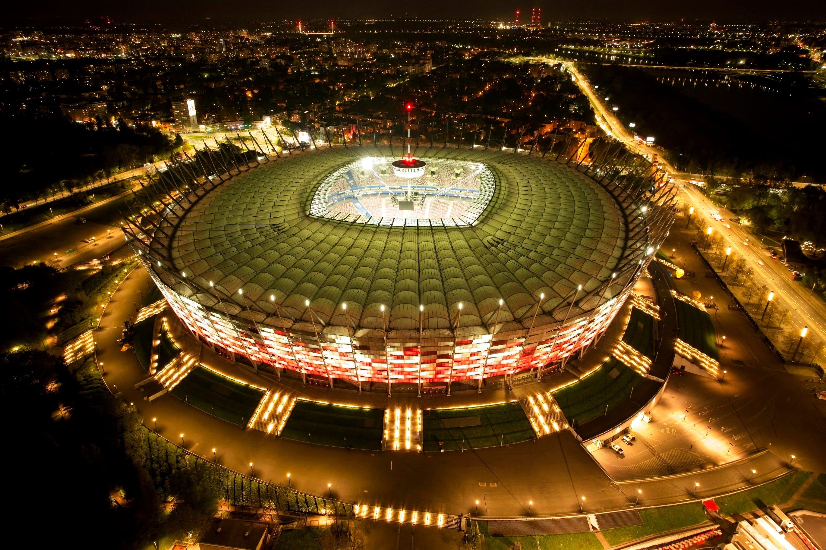 Aerial view of a large stadium lit up at night within a city